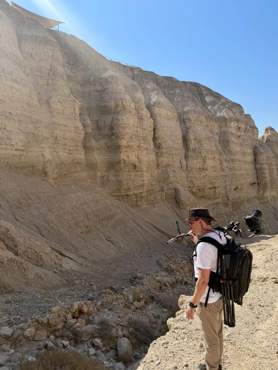 Joshua Swanson hiking the cliffs of Qumran with a camera rig on assignment for CBN News